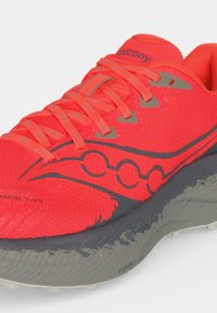 Φωτεινό κόκκινο αθλητικό παπούτσι Saucony με γκρίζα σόλα, γκρίζο λογότυπο και ταιριαστά κόκκινα κορδόνια, εμφανιζόμενο από εμπρόσθια πλευρική γωνία.