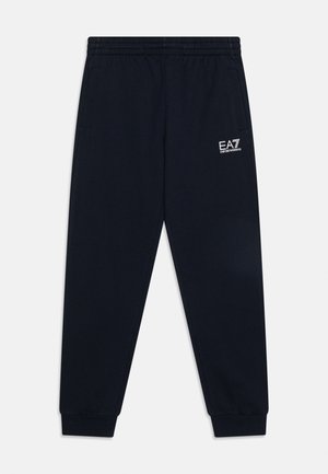Pantalon de survêtement noir fuselé avec taille et poignets élastiques, poches avant, et logo blanc EA7 Emporio Armani sur la cuisse droite.