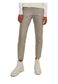 Pantalon à carreaux marron et blanc, coupe slim, avec un tissu texturé. Associé à des bottines blanches à semelle épaisse.