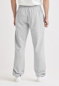 Lysegrå joggingbukser med elastisk taljebånd, sidelommer og afsmalnende manchetter. Stoffet er blødt med en struktureret overflade.