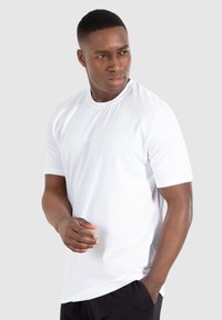 White short-sleeve t-shirt made of cotton, featuring a rounded neckline and textured "SMILDOX" logo on the chest. Simple design.