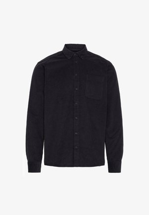 Melna korduroja krekls ar garām piedurknēm, pogas uz leju, priekšējo kabatu un pogu rindu. Audumam ir teksturēta izgaismojuma izskats.