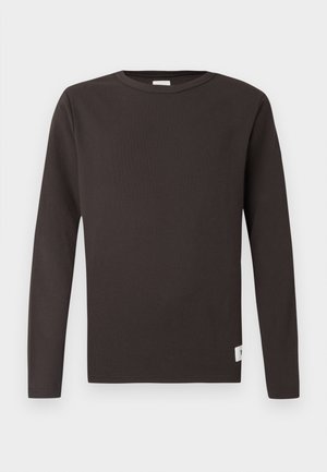 Tumedate rinna-särk tumepruuni värviga, valmistatud ribakujulisest puuvillast. Omab ümarat kaelust, sirget lõiget ja väikest sildi aktsenti alumisel serval.