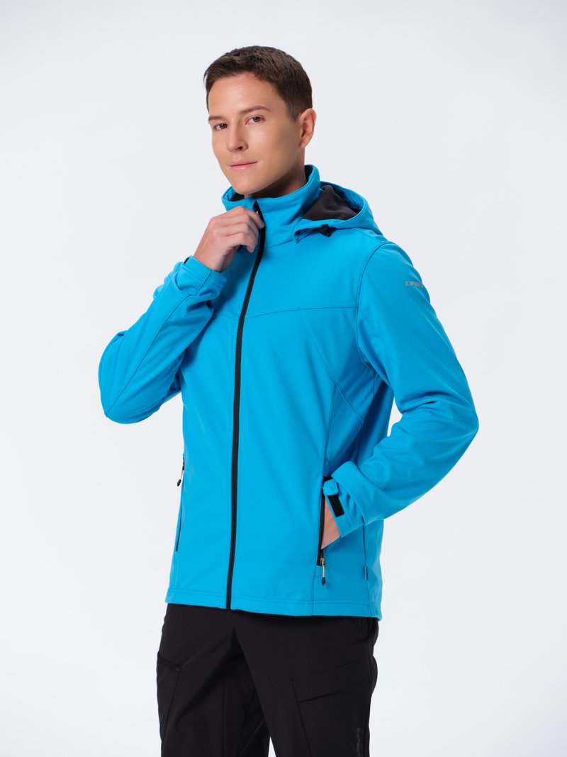 Blå softshell jakke med hætte, lynlås foran og sorte accenter. Har to sidelommer, letvægtsstof og en tætsiddende design.