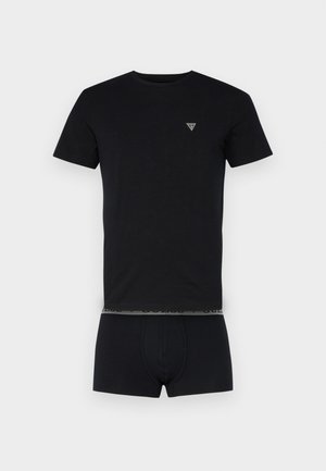 Must must t-särk lühikeste varrukatega, ümmargune kaelus ja väike kolmnurkne logo rinnal, koos sobivate mustade aluspükstega.