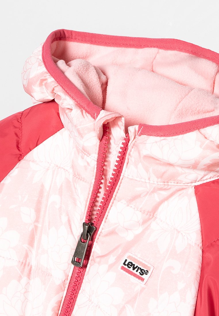 Giacca trapuntata rosa con motivo floreale, maniche rosse a contrasto, cappuccio foderato in pile e zip con tirazip brandizzato.