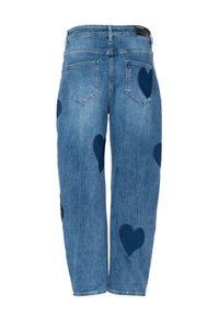 Jeans di denim blu con toppe a forma di cuore blu scuro sulle gambe e sulle tasche posteriori, mostrati da un punto di vista posteriore.