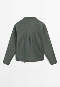 Veste verte texturée avec col, manches longues et un pli au dos. Présente une coupe courte et décontractée avec des ajustements par cordon de serrage.