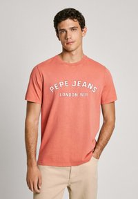 Ružovo-oranžové bavlnené tričko s okrúhlym výstrihom a krátkymi rukávmi. Na prednej strane je vyvedený text "PEPE JEANS LONDON W11" v bielej farbe.