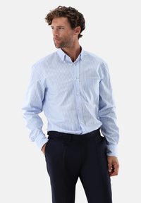 Camicia a righe blu e bianche con bottoni e taschino sul petto, realizzata in tessuto leggero. Presenta un colletto classico e maniche lunghe.