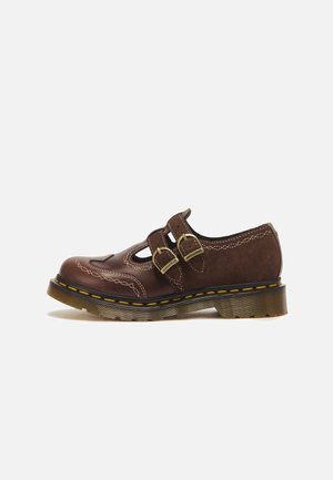 Brauner Lederschuh mit geschlossenem Zehenbereich, zwei Schnallen, dekorativer Naht und dicker, transparenter Gummisohle mit gelber Naht.