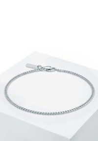 Bracciale in argento con maglie intrecciate, dotato di chiusura a gabbiano e di un piccolo tag con logo. Finitura liscia e lucida su uno sfondo bianco.