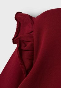 Top burdeos con detalles de mangas con volantes, que presenta una textura de punto suave y un diseño ajustado. Sin cierres visibles ni patrones.