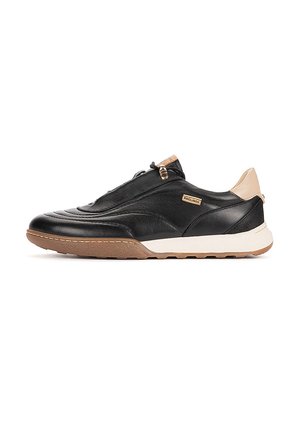 Zapatilla baja de cuero negro con talón beige y suela de goma marrón, con etiqueta de marca lateral y cierre de cremallera sobre fondo blanco.
