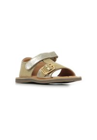 Sandalias beige con tira metálica dorada, hebilla ajustable, diseño de puntera abierta, suela plana y plantilla acolchada para mayor comodidad.