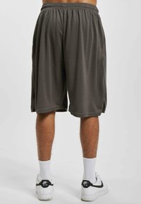 Grå treningsshorts med elastisk midje, knelange, laget av myk stoff; kombinert med hvite sokker og hvite joggesko med svarte detaljer.