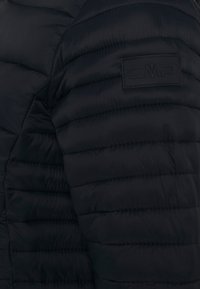 Sort polstret jakke med en quiltet tekstur, CMP-logo patch og et tætsiddende design med vandret syninger over overfladen.
