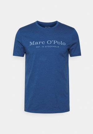 T-shirt en coton bleu marine avec un col rond et des manches courtes. Présente un texte imprimé en blanc : "Marc O'Polo EST. À STOCKHOLM."