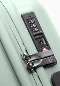 Valise vert clair avec un cadenas à combinaison, deux zips argentés et une finition texturée pour plus de durabilité. Comprend un emplacement pour un cadenas TSA.