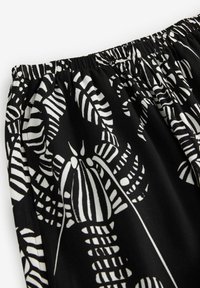 Tissu noir avec un motif audacieux de feuilles blanches et de rayures. La taille élastique avec fronces améliore l'ajustement et le confort.