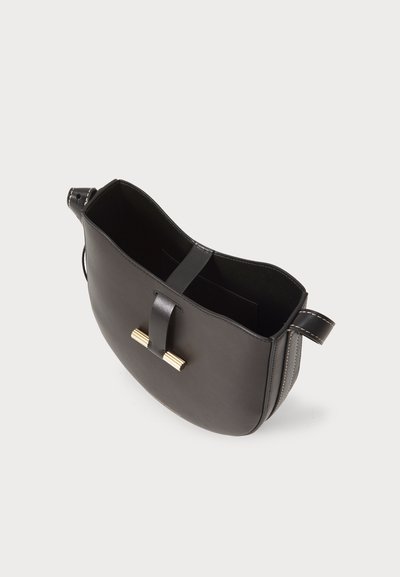 Melna ādas plecu soma ar gludu tekstūru, izliektu formu, kontrastējošu šuvju un centrālu zelta krāsas aparatūras akcentu.