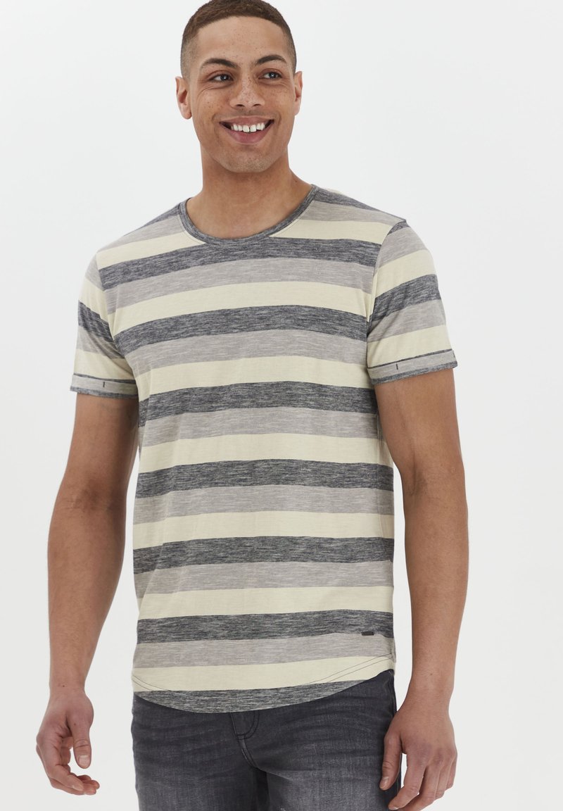 Camiseta de rayas con cuello redondo, que presenta rayas alternas en gris y crema, mangas cortas y un sutil detalle en el dobladillo.