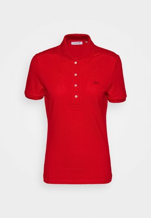 Red polo shirt made of cotton with short sleeves, three-button placket, and a small embroidered logo on the left chest.