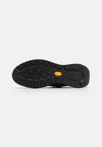 Suola in gomma nera con un motivo testurizzato per la presa, caratterizzata da un logo Vibram arancione prominente al centro e progettata per il grip.