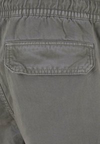 Grijze stoffen broek met een elastische tailleband, een achterzak met flap en een subtiele textuurpatroon.