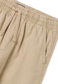 Pantalones cortos beige con cordón hechos de una tela ligera, con cintura elástica, bolsillos laterales y una textura suave.