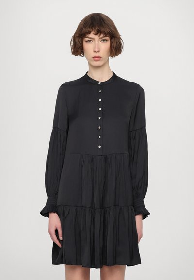 Abito nero con colletto, maniche lunghe e voluminose, e gonna a strati. Presenta bottoni decorativi lungo la parte anteriore e una texture sottile.