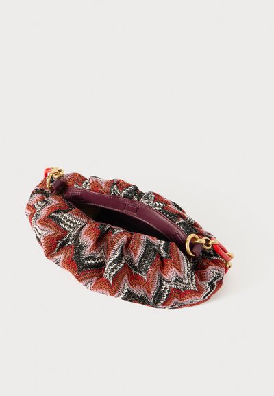 Vävd clutchtaske med en volangdesign i röd, svart och vit zigzag-mönster. Har detaljer i guldfärg och ett djupt lila inre.