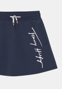 Marineblauwe rok van zacht materiaal met een wit diagonale tekstontwerp en een elastische tailleband met verstelbare trekkoorden.