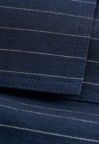 Marine stof met witte streepjes, met een gladde textuur en zichtbare stikdetails. De randen zijn netjes afgewerkt, wat de kwaliteit benadrukt.
