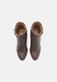 Brune lær ankle boots med en slank, spiss tå. Har en sidebøyle detalj og en jevn overflate med en tan innvending.
