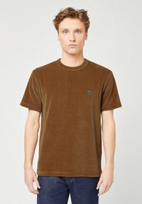 Bruine corduroy t-shirt met een ronde halslijn en korte mouwen, met een klein groen boompje geborduurd op de borst.
