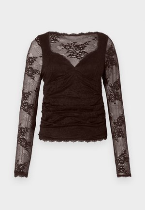 Haut marron foncé à manches longues avec superposition en dentelle, présentant un décolleté en V, un devant plissé et un ourlet festonné. Le tissu texturé accentue le design.