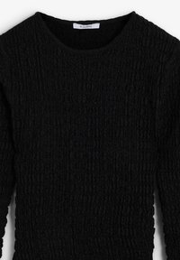 Zwarte gebreide trui met een ronde halslijn en lange mouwen. De stof heeft een gekreukel patroon voor extra dimensie. Merkenlabel zichtbaar.