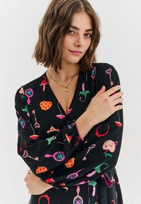 Czarna sukienka z kolorowymi, fantazyjnymi wzorami kluczy, koron i owoców. Długie rękawy z elastycznymi mankietami i dekoltem w serek.