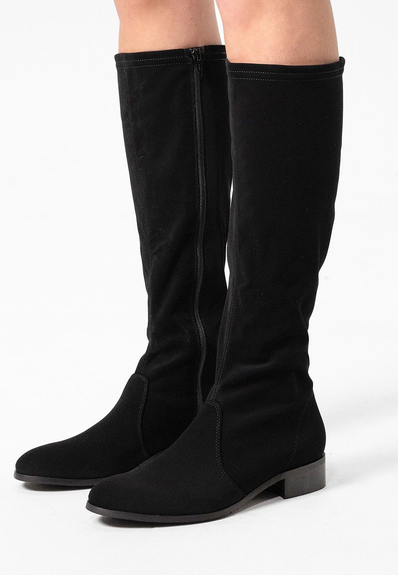 Black suede knee-high boots with a pointed toe, side zipper, and flat heel. Smooth texture with stitched detailing along the seams.