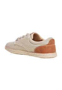 Sneaker in tela beige con un accento in pelle marrone sul tallone, punta rotonda e suola in stile juta intrecciata. Chiusura con lacci e tessuto dal design texture.