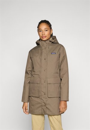 Bruine, waterdichte parka met een capuchon, twee grote vo zakken en drukknopen. De stof heeft een gladde, matte afwerking.