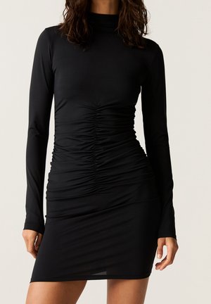 Schwarzes langärmeliges Kleid mit hohem Kragen, das über geraffteDetails an den Seiten und einen glatten, dehnbaren Stoff verfügt.