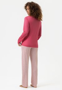 Haut rose à manches longues associé à un pantalon de pyjama rose clair arborant un petit motif floral. Tissu doux avec une coupe décontractée.