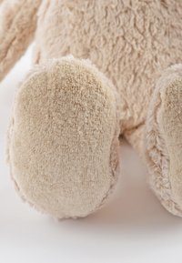 Light beige plush toy feet with soft, fuzzy texture; rounded shape with smooth and shaggy sections; minimal stitching visible.