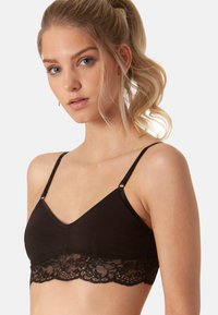 Bralette nera con parte superiore in cotone morbido e pizzo lungo l'orlo, con spalline regolabili e scollatura a V.