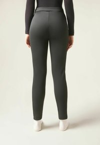 Svarta leggings i ett mjukt, stretchigt material, med hög midja och åtsittande design som smalnar av vid vristerna, bärs med vita strumpor.