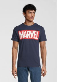 Mörkblå bomull T-shirt med ett stort röd "MARVEL"-tryck i blockbokstäver. Korta ärmar och rundad halsringning. Avslappnad passform.