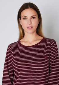 T-shirt a maniche lunghe color bordeaux con strisce orizzontali beige, scollatura tonda, texture a coste e piccolo logo sul petto.