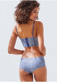Denim bralet in svetlo modri barvi in visoke hlačke; vsebuje prilagodljive naramnice in zaponko na hrbtni strani.